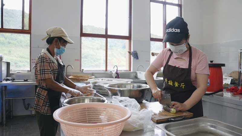 西盟縣委黨校的食堂里，勐梭鎮(zhèn)勐梭村村民歐少正與同事忙著摘菜、洗菜，做好餐前準(zhǔn)備工作。-艾嘎攝-2023年7月4日